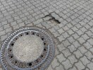 Foto: Pflastersteine, Absenkung bei einem Schachtdeckel auf der Straße Zu den Elsterwiesen, Zum Pintegraben   